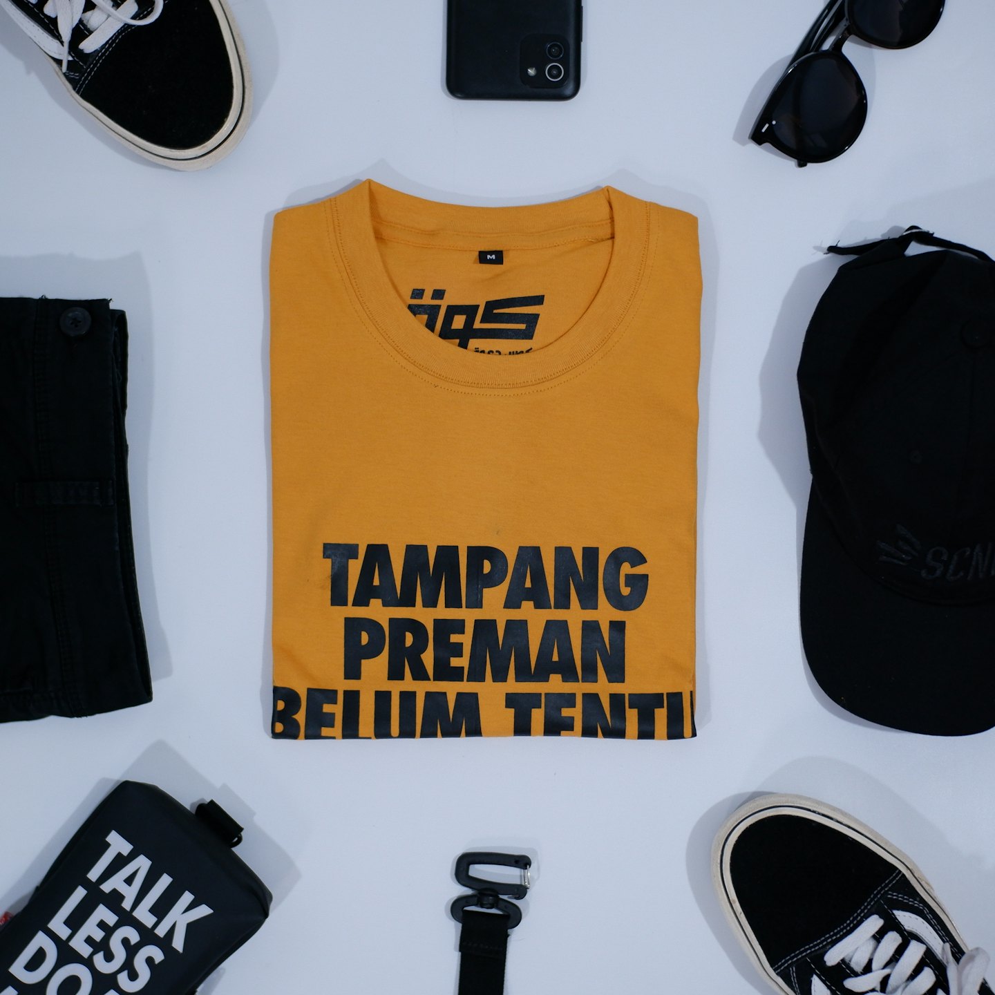 Mustard yellow t-shirt and black accessories laid out neatly.