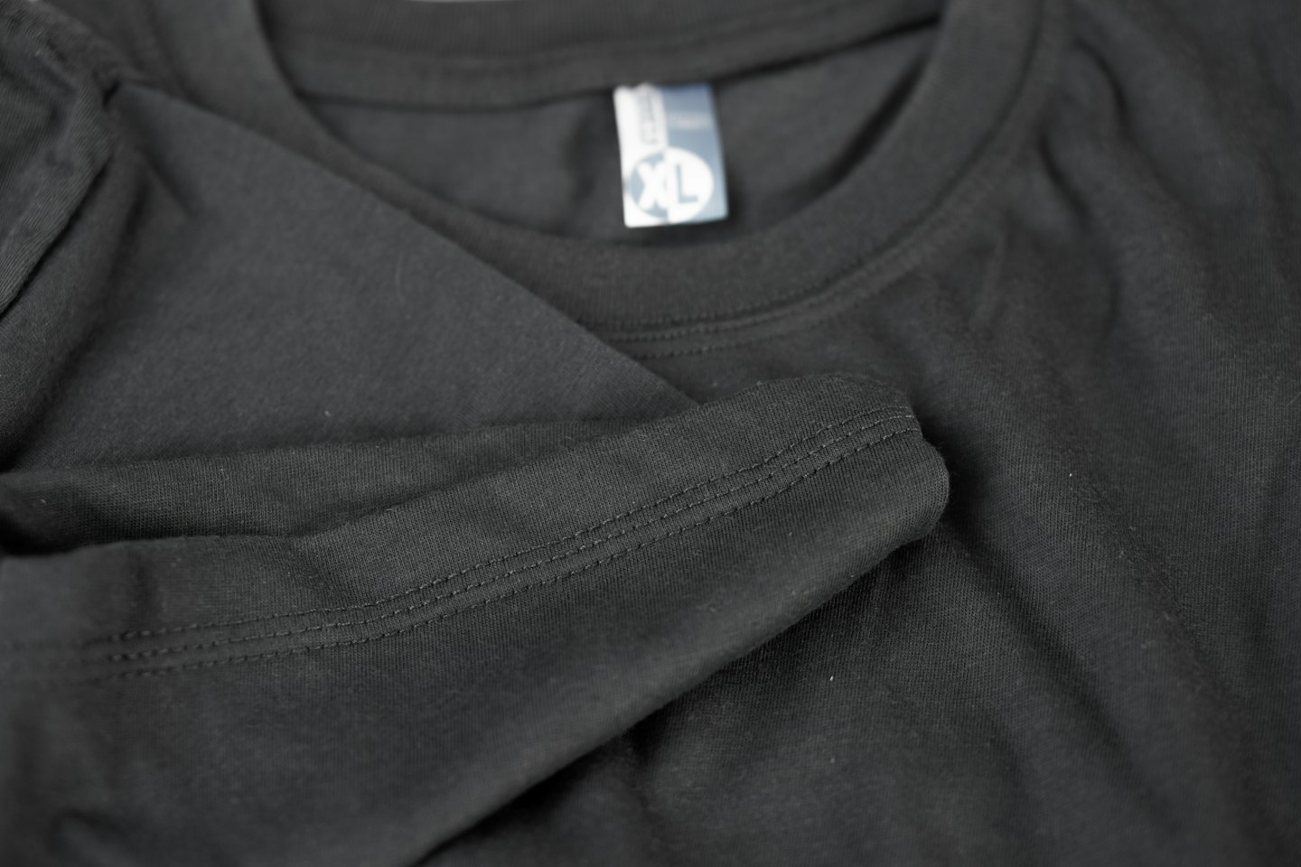 Folded black long-sleeved shirt with a visible clothing label.