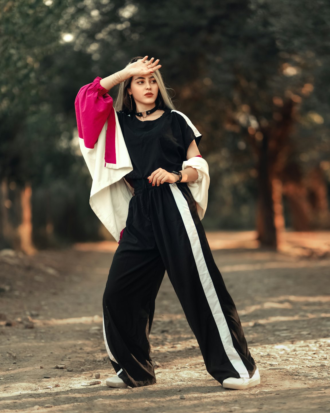 Woman in a fuchsia jacket shielding her eyes on a path.