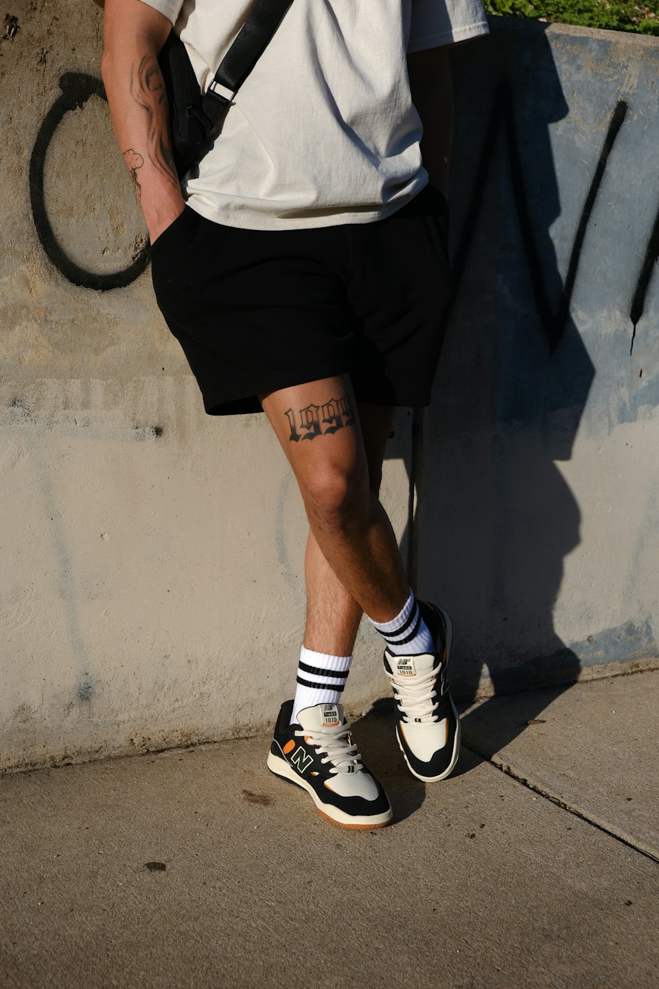 Person in casual clothing leans against a weathered concrete wall.