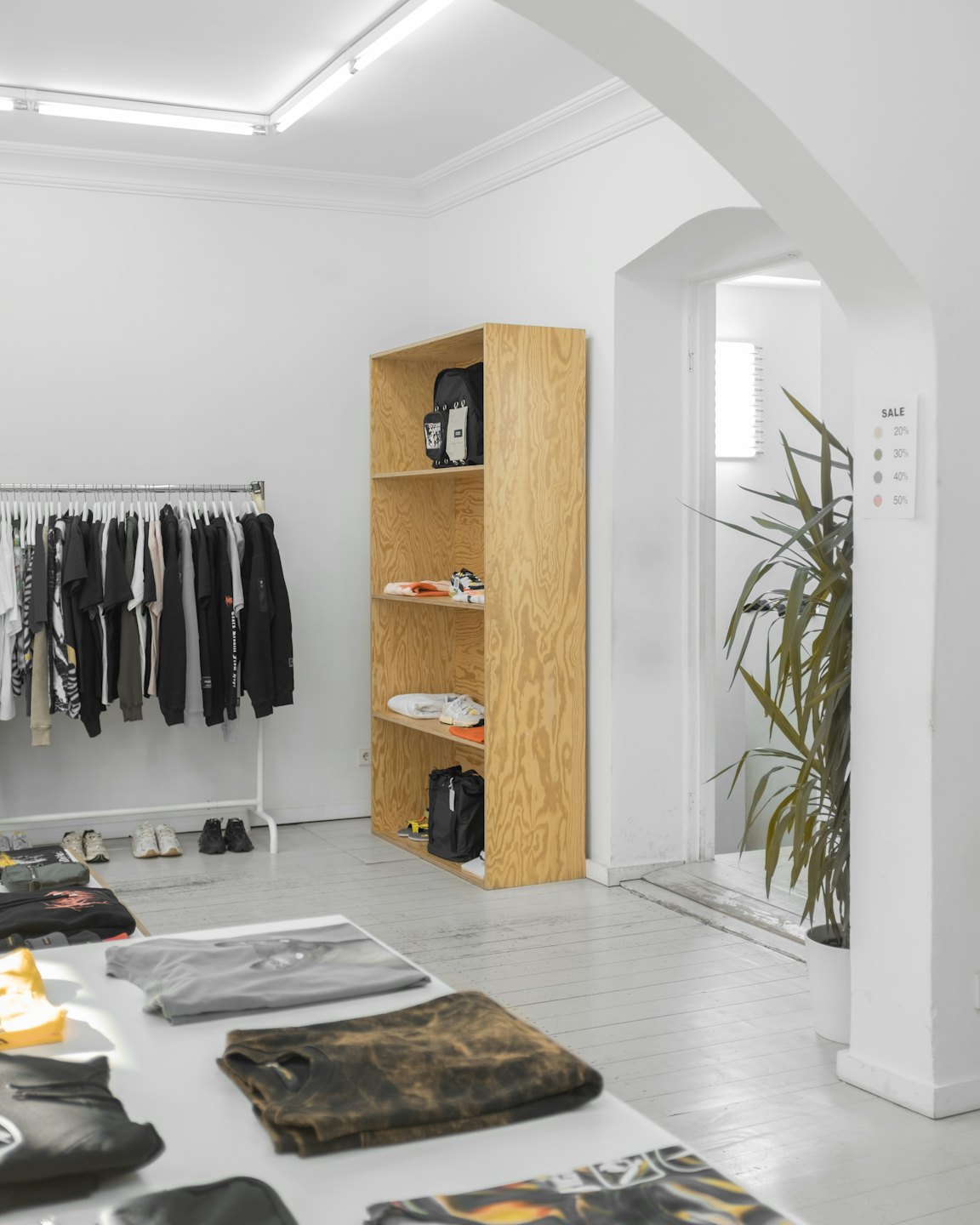 Minimalist clothing store interior with display tables and racks.